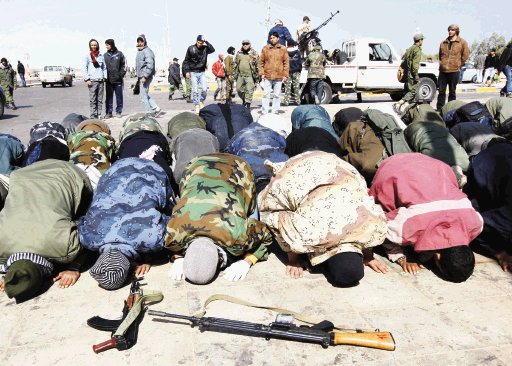 Varios rebeldes libios rezan en Ras Lanuf de Libia. EFE.