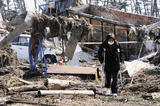 Una mujer camina entre los escombros utilizando muletas y una mascarilla. Sendai ofrece un panorama desolador. EFE.