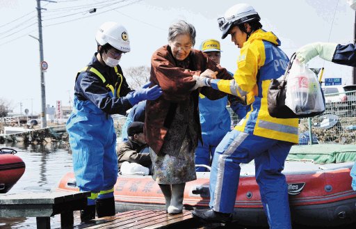 Efectivos de las Fuerzas de Autodefensa japonesas ayudan a una anciana tras su rescate en la localidad de Ishinomaki. EFE.