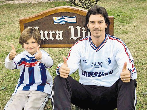  “Mi casa es como la ONU”. Claudio Ciccia y su hijo Alessandro, de 8 años, afuera de la casa en Uruguay, con la leyenda “Pura Vida”.Cortesía.