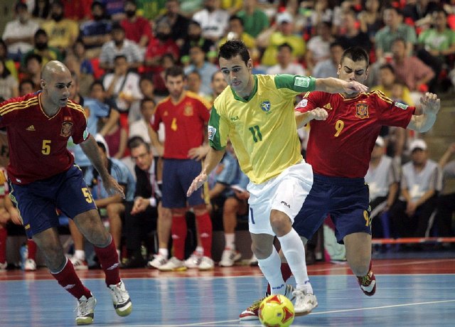 Brasil logra otro pentacampeonato al vencer a España. El jugador de la selección de Brasil, Neto (c), presionado por los jugadores de España Fernandao (i) y Lozano, durante la final del Mundial de fútbol sala que se disputa en Tailandia. EFE.